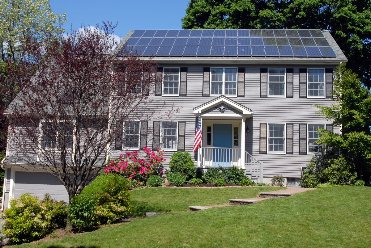 A gray home with rooftop solar panels, shown as an illustrative example.